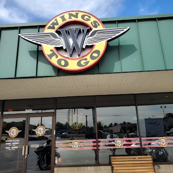 The exterior of a Wings to Go restaurant with its logo prominently displayed above the entrance.
