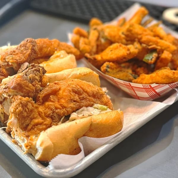 A tray of crispy fried chicken sandwiches with coleslaw and a side of seasoned fries.